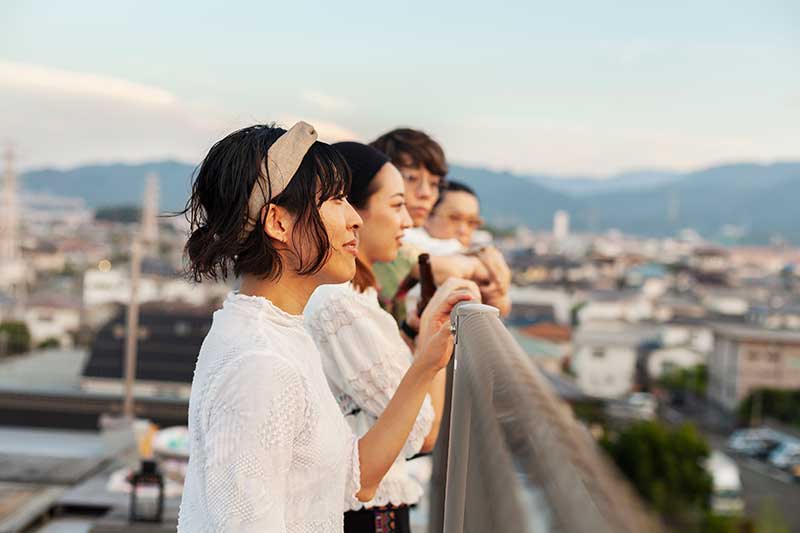 group-of-young-japanese-men-and-women-standing-on-a-rooftop-in-an-urban-setting-